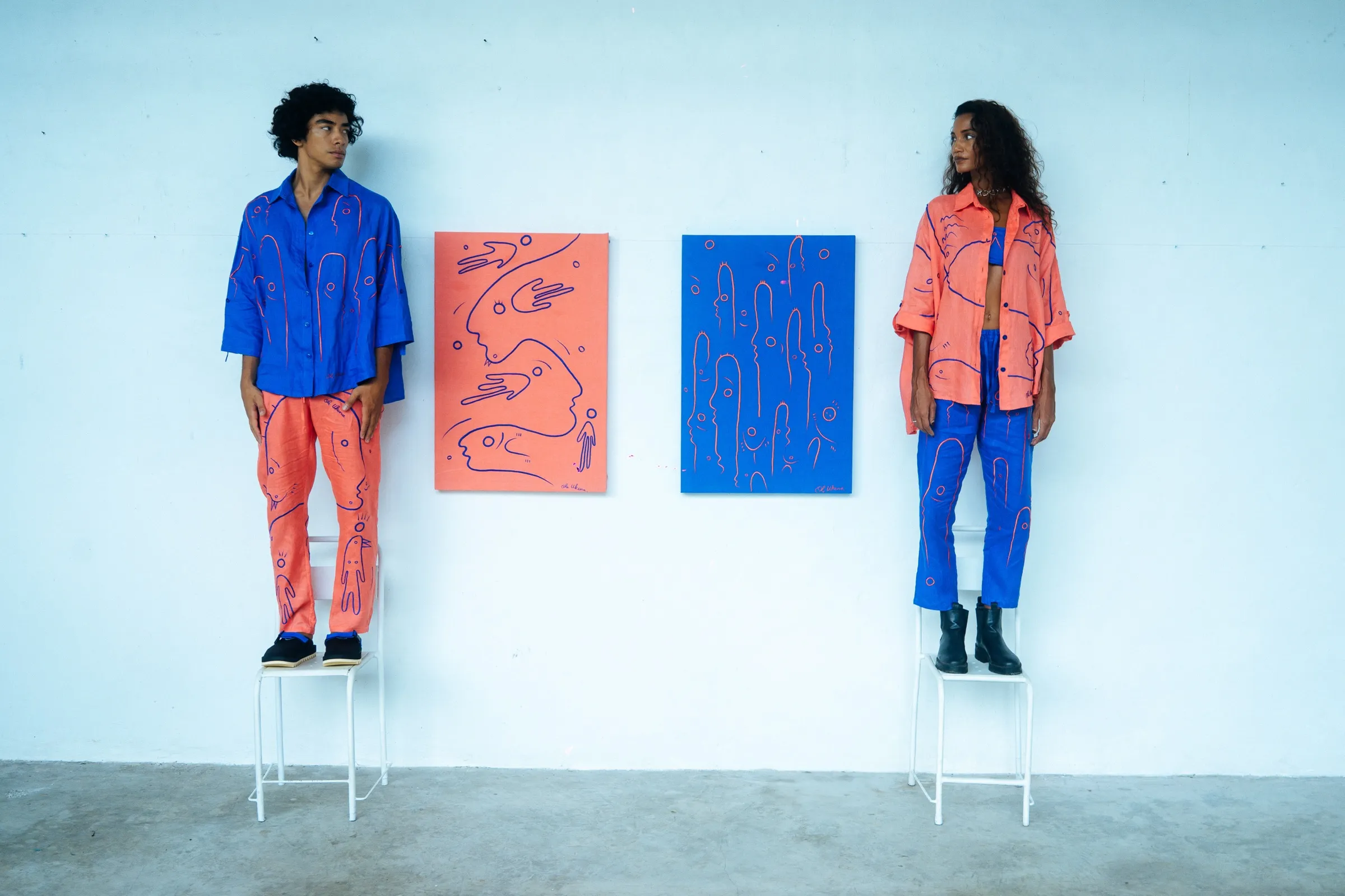UKENA campaign — coral and blue linen sets beside the canvases they echo